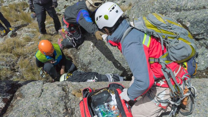 Climbers on a rock face with a first aid kit open