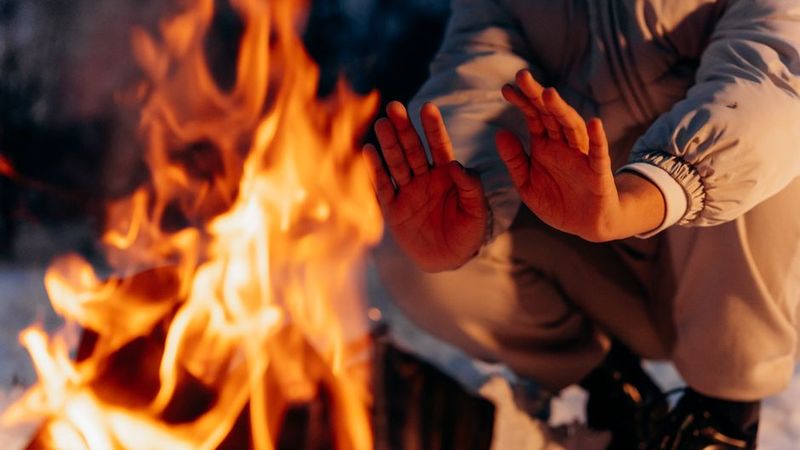 Hands warming over firelight in the dark
